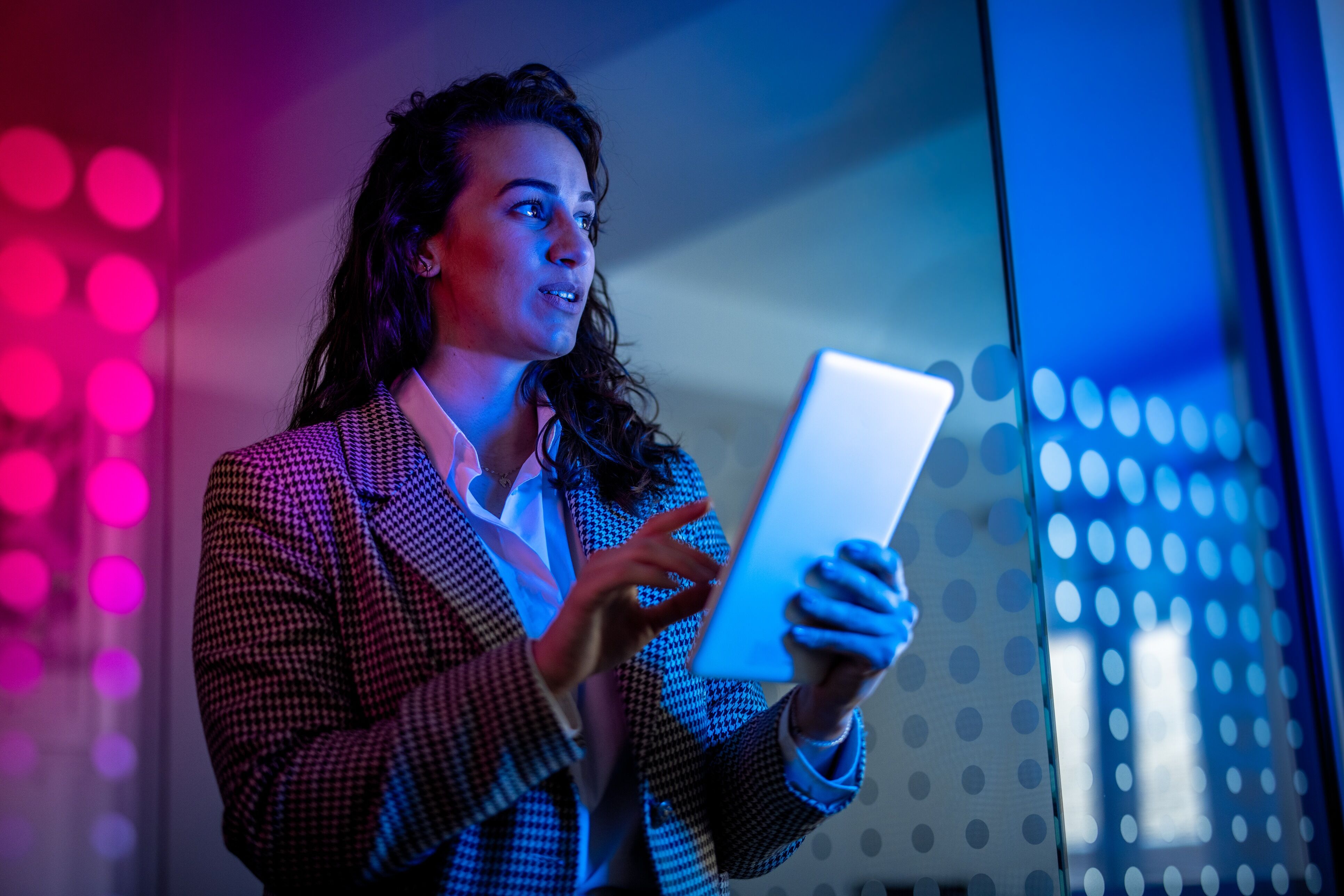 Young female field service professional in modern office setting holding tablet computer.